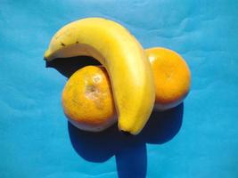 naranja y plátano sobre un fondo azul.tono frío.vista superior. foto