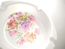 white cigarette ashtray with floral motif in the middle. ashtray isolated on a white background.  Ashtrays are often used by smokers to dispose of cigarette ashes or cigarette butts photo