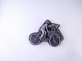 refrigerator magnet in the form of a rickshaw, pedicab is one of the means of transportation in Indonesia. fridge magnet isolated on a white background.high angle view. photo