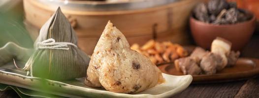 Rice dumpling - Chinese zongzi food in a steamer on wooden table with red brick wall, window background at home for Dragon Boat Festival concept, close up. photo