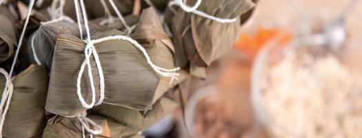 Rice dumpling zongzi making - wrapping Chinese rice dumpling zongzi on table at home for Dragon Boat Festival celebration, close up, lifestyle. photo