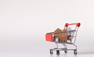 Small wooden house in small shopping cart on white background and copy space photo