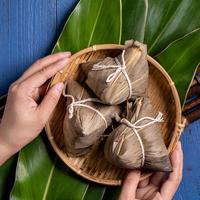 Rice dumpling, zongzi - Traditional Chinese food on green leaf background of Dragon Boat Festival, Duanwu Festival, top view, flat lay design concept. photo