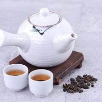 té caliente en tetera blanca y tazas en un tamiz sobre fondo de cemento gris brillante, primer plano, concepto de diseño de espacio de copia. foto