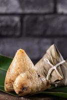 Rice dumpling, zongzi - Chinese rice dumpling zongzi on black brick background slate table, concept of Dragon Boat Festival traditional food, close up. photo