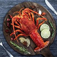 Cooked boiled lobster, delicious dinner seafood meal set with knife and fork on black stone slate background, restaurant menu design, top view, overhead photo