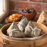 dumpling de arroz, zongzi - dumpling de arroz chino zongzi en un vapor sobre una mesa de madera con ladrillo rojo, fondo de ventana en casa para el concepto del festival del bote del dragón, de cerca. foto