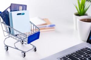 Office online paying, stay home shopping, electronic payment with credit card concept, laptop on white table background with shop cart, close up.