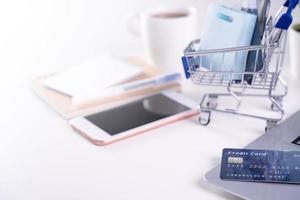 Office online paying, stay home shopping, electronic payment with credit card concept, laptop on white table background with shop cart, close up. photo