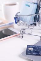 Office online paying, stay home shopping, electronic payment with credit card concept, laptop on white table background with shop cart, close up. photo