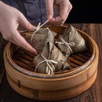 Rice dumpling, zongzi - Dragon Boat Festival, Bunch of Chinese traditional cooked food in steamer on wooden table over black background, close up, copy space photo