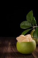 Fresh pomelo, pummelo, grapefruit, shaddock on wooden table over black background, close up, copy space. Fruit for Mid-autumn festival. photo