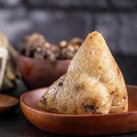 dumpling de arroz, zongzi - dumpling de arroz chino zongzi sobre una mesa de pizarra de fondo de ladrillo negro, concepto de comida tradicional del festival del barco del dragón, de cerca. foto