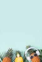 Funny pineapple wearing white headphone, concept of listening music, isolated on colored background with tropical palm leaves, top view, flat lay design. photo