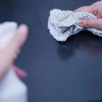 la mujer joven está sosteniendo una botella de spray, un trapo para limpiar, limpiar la superficie de alojamiento del estante del gabinete de metal de la oficina, cerrar, estilo de vida, concepto de antibacteriano. foto