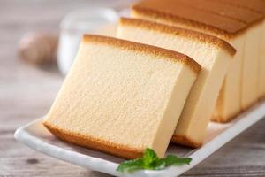 Castella - Delicious Japanese sliced sponge cake food on white plate over rustic wooden table, close up, healthy eating, copy space design. photo
