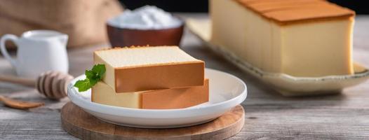 Castella - Delicious Japanese sliced sponge cake food on white plate over rustic wooden table, close up, healthy eating, copy space design. photo