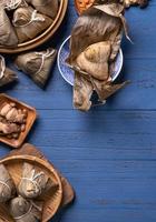 Dragon Boat Festival concept - Rice dumpling, zongzi, traditional Chinese food on blue wooden background for Duanwu Festival, top view, flat lay design concept. photo