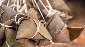 dumpling de arroz - comida china zongzi en un vapor sobre una mesa de madera con pared de ladrillo rojo, fondo de ventana en casa para el concepto del festival del bote del dragón, de cerca. foto