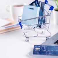 Office online paying, stay home shopping, electronic payment with credit card concept, laptop on white table background with shop cart, close up. photo