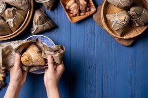 zongzi - bola de arroz con concepto del festival del bote del dragón, comida tradicional china sobre fondo de madera azul para el festival duanwu, vista superior, concepto de diseño plano. foto