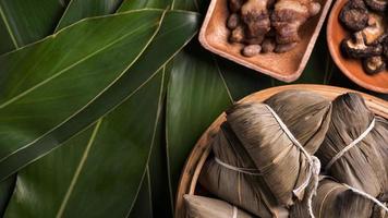 Rice dumpling, zongzi - Traditional Chinese food on green leaf background of Dragon Boat Festival, Duanwu Festival, top view, flat lay design concept. photo