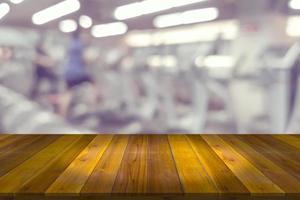 Empty wooden board space platform with blur fitness gym equipment background photo