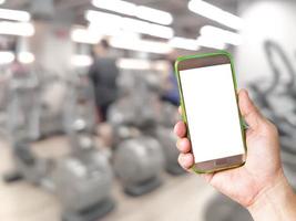 hand holding mobile smart phone with blur fitness gym equipment background photo