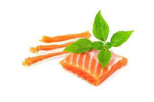 Piece of fresh salmon fillet sliced with leaf basil isolated on white background photo