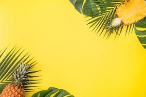 Beautiful pineapple on tropical palm monstera leaves isolated on bright pastel orange yellow background, top view, flat lay, overhead above summer fruit. photo