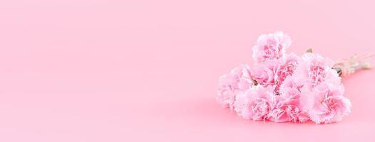 Mother's Day holiday gift design concept, pink carnation flower bouquet with wrapped box isolated on light pink background, copy space. photo