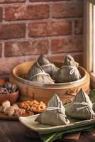 Rice dumpling, zongzi - Chinese rice dumpling zongzi in a steamer on wooden table with red brick, window background at home for Dragon Boat Festival concept, close up. photo