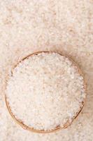 Raw rice in a bowl and full frame in the white background table, top view overhead shot, close up photo