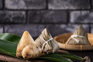 dumpling de arroz, zongzi - dumpling de arroz chino zongzi sobre una mesa de pizarra de fondo de ladrillo negro, concepto de comida tradicional del festival del barco del dragón, de cerca. foto