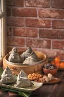 Zongzi - Chinese rice dumpling zongzi in a steamer on wooden table with red brick, window background at home for Dragon Boat Festival concept, close up. photo