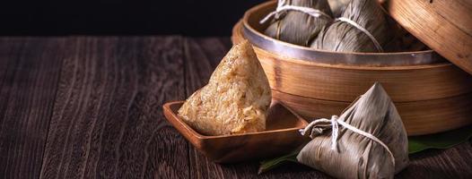 Zongzi - Chinese rice dumpling zongzi in a steamer on wooden table black retro background for Dragon Boat Festival celebration, close up, copy space. photo