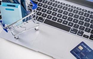 Office online paying, stay home shopping, electronic payment with credit card concept, laptop on white table background with shop cart, close up. photo