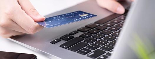 Office online paying, stay home shopping, electronic payment with credit card concept, laptop on white table background with shop cart, close up. photo