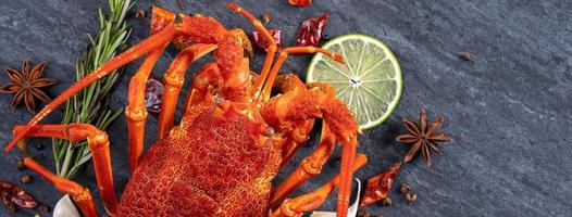 Cooked boiled lobster, delicious dinner seafood meal set with knife and fork on black stone slate background, restaurant menu design, top view, overhead photo