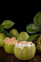 Fresh pomelo, pummelo, grapefruit, shaddock on wooden table over black background, close up, copy space. Fruit for Mid-autumn festival. photo