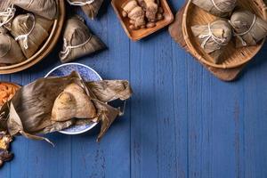 zongzi - bola de arroz con concepto del festival del bote del dragón, comida tradicional china sobre fondo de madera azul para el festival duanwu, vista superior, concepto de diseño plano. foto