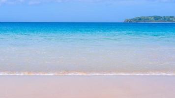 hermosa playa de arena de color dorado increíble con olas suaves aisladas con un cielo azul soleado. concepto de idea de turismo tropical tranquilo, espacio de copia, primer plano foto