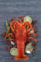 Cooked boiled lobster, delicious dinner seafood meal set with knife and fork on black stone slate background, restaurant menu design, top view, overhead photo