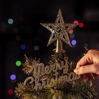 Christmas background concept- beautiful decor bauble hanging on the Christmas tree with sparkling light spot, blurry dark black background, copy space, close up. photo