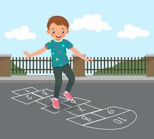 cute little boy playing hopscotch drawn with chalk outside on playground street at the park