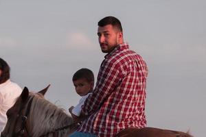 Father and son enjoy riding horses together by the sea. Selective focus photo