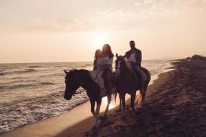 The family spends time with their children while riding horses together on a beautiful sandy beach on sunet. photo