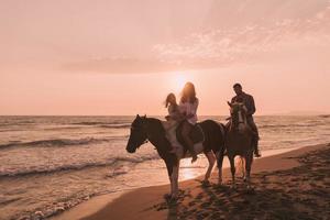 la familia pasa tiempo con sus hijos mientras montan a caballo juntos en una playa de arena. enfoque selectivo foto