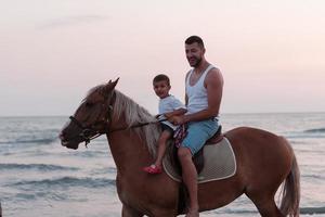 Father and son enjoy riding horses together by the sea. Selective focus photo