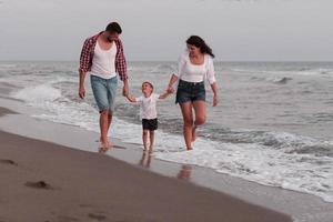 The family enjoys their vacation as they walk the sandy beach with their son. Selective focus photo